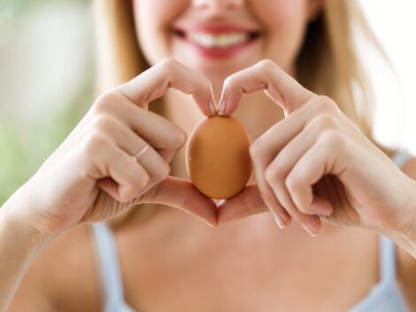 imagen de mujer joven sujetando un huevo y formando un corazón con los dedos